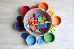 Bowl with various shapes and colors and tongs that are used to help sort the items by their attribute.  This looks like a matching game, which helps boost children's language skills and other abilities as well.